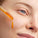 This image shows a close-up of a person applying Elixir, a radiance-boosting omega oil, to their cheek using a dropper. The golden hue of the oil reflects its rich, nourishing formula packed with essential omegas. The product is designed to deeply hydrate and enhance the skin's natural glow, leaving it smooth and radiant.